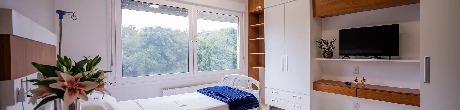 Quarto privativo com cama hospitalar e mobiliário planejado