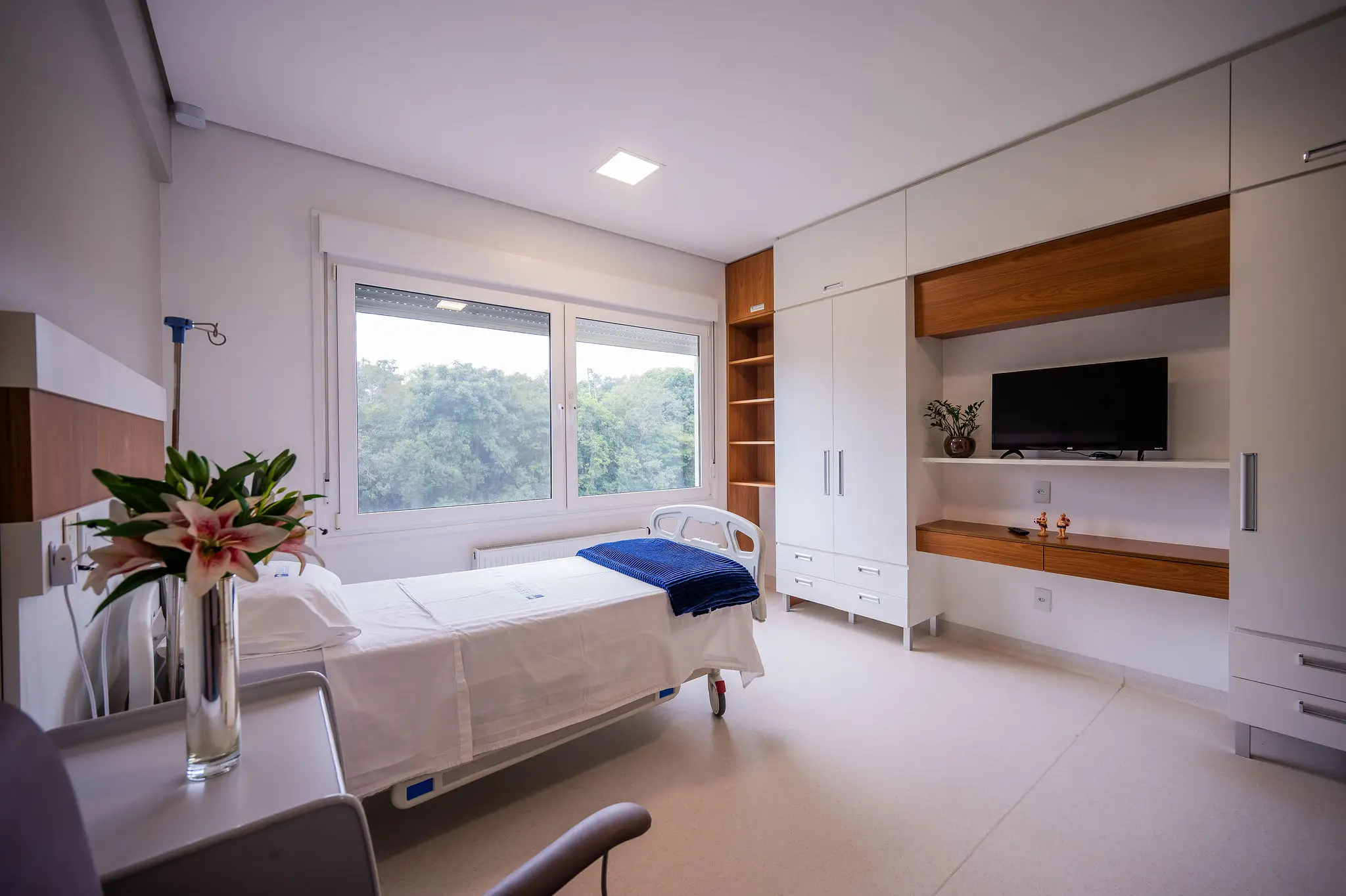 Quarto claro do Serraville com cama hospitalar, janela ampla e mobiliário planejado