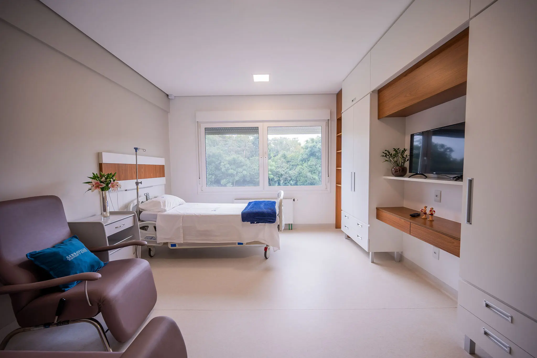 Suíte ampla com cama hospitalar, poltrona e armários planejados